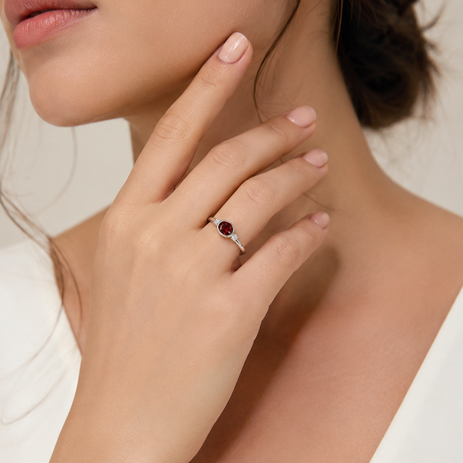 Woman wearing a ring with a red gemstone on a neutral background