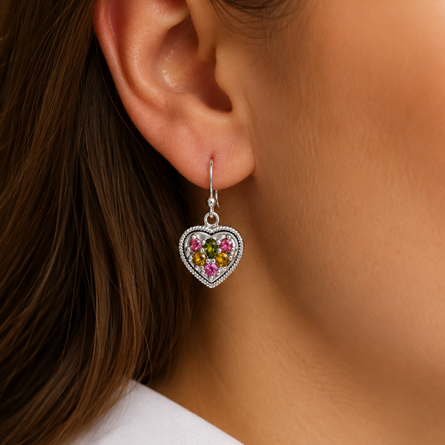 Heart-shaped earring with colorful gemstones worn by a person