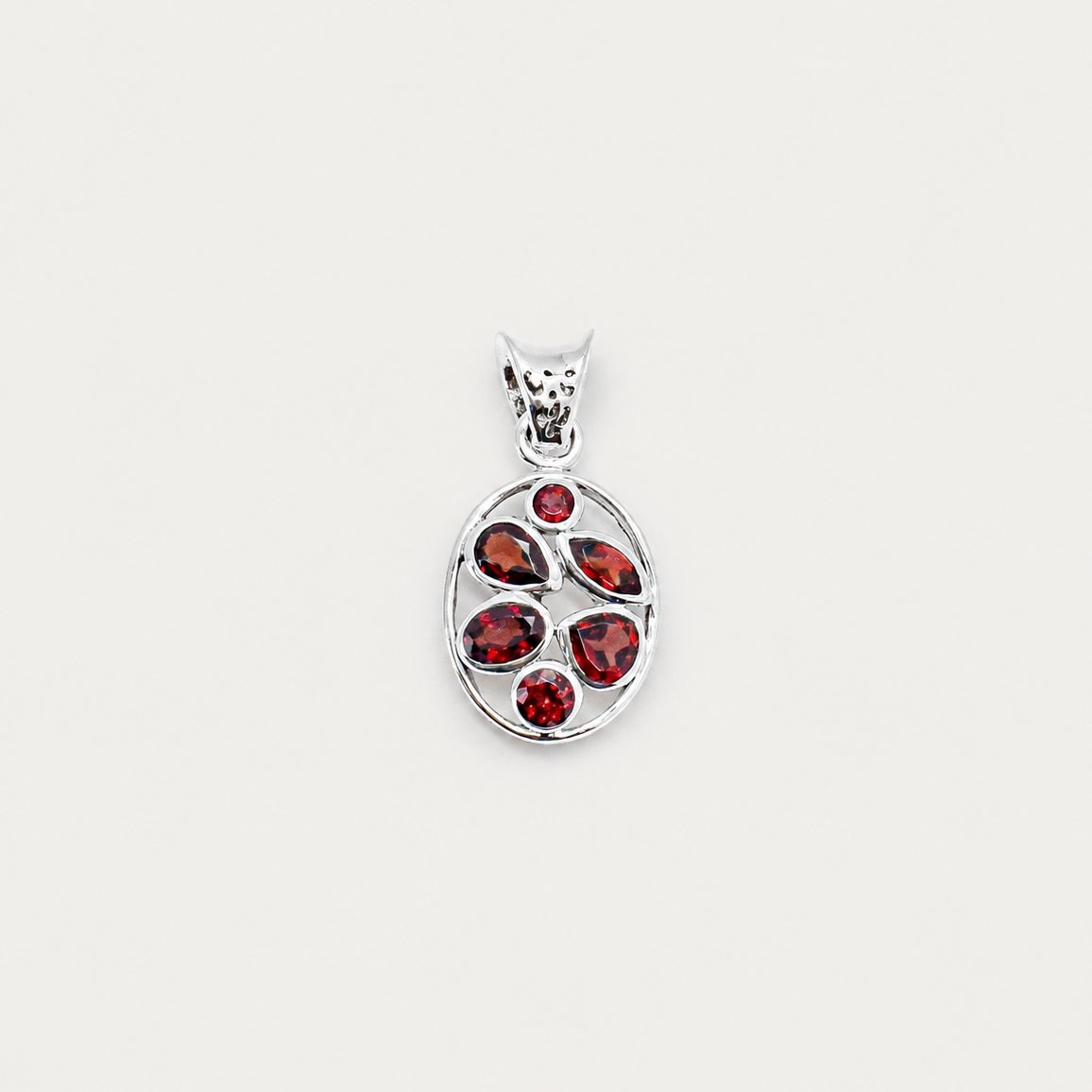 Silver pendant with red gemstones on a white background